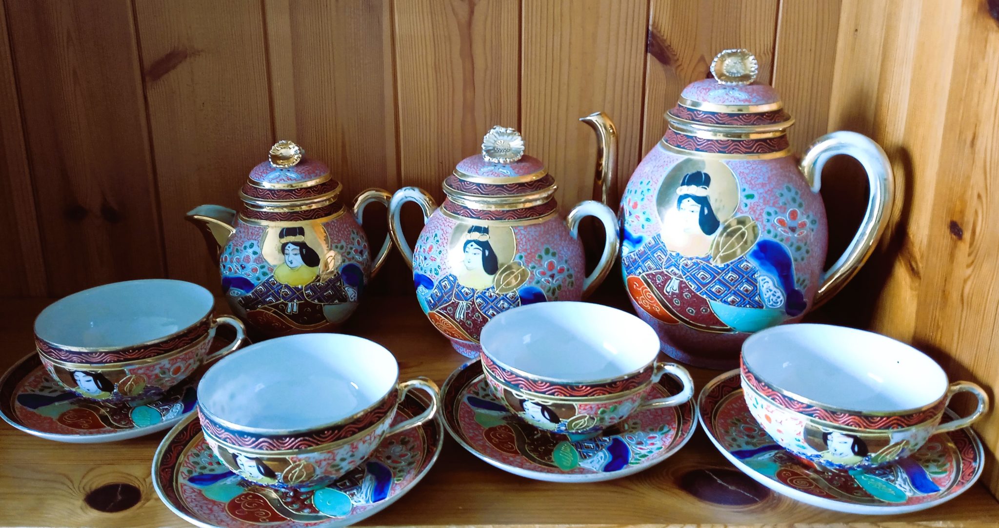 Service à thé japonais composé de 4 tasses et leurs sous tasses, d'un sucrier, d'un pot à lait, et d'une théière au motif geisha, dans les tons bleu, rose, rouge, doré