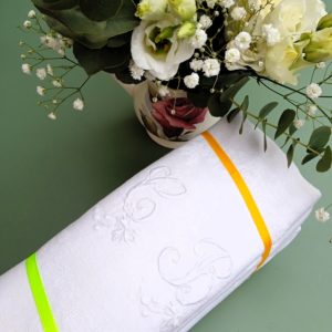 Lot de six serviettes blanches brodées présentées avec des fleurs