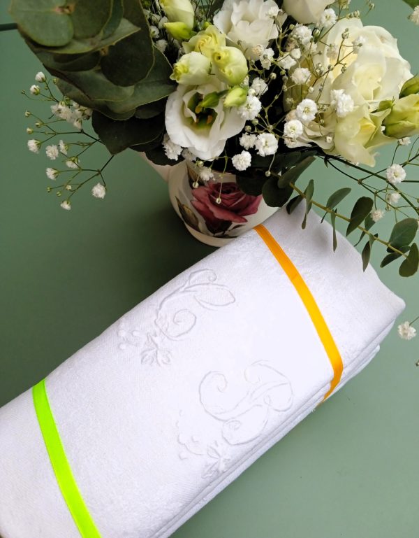 Lot de six serviettes blanches brodées présentées avec des fleurs