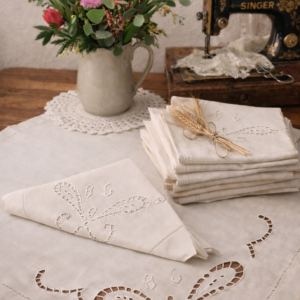 Présentation des serviettes en coton brodées et motif ajouré, une dépliée, un pliée en deux et les autres en pile
